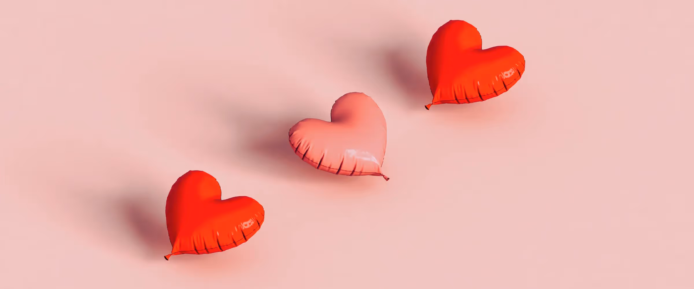 Three heart-shaped balloons in pink and red.