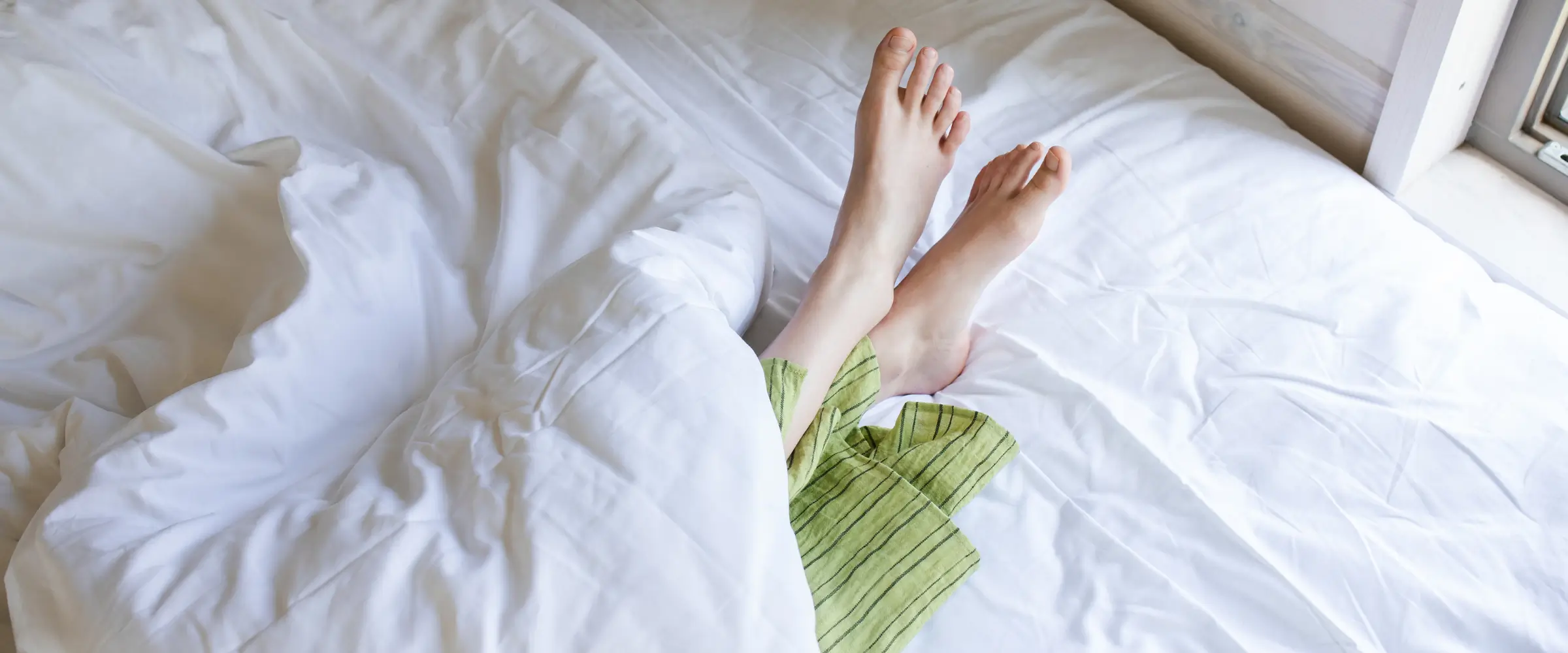 Bare feet poking out from beneath the bed covers.