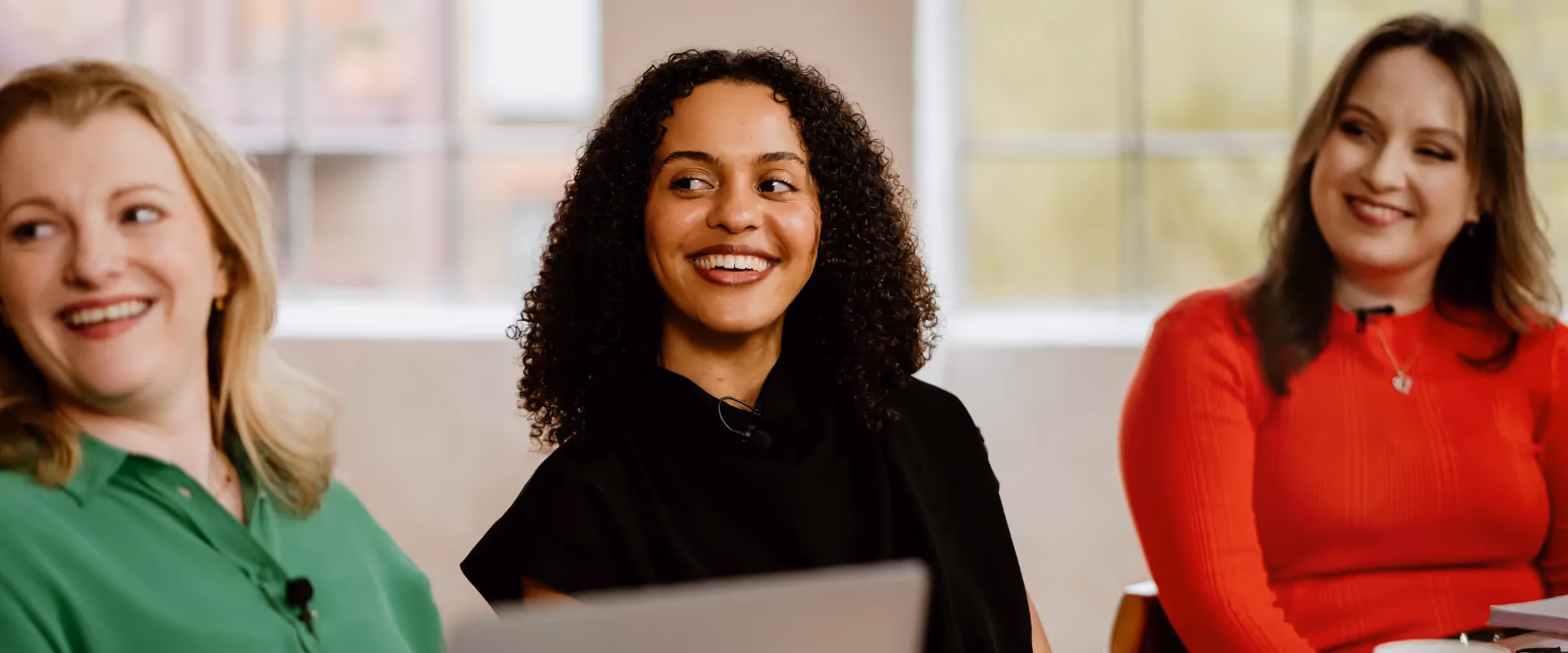 The Novelry editors (L-R) Lizzy Goudsmit Kay, Sadé Omeje, and Sorcha Rose sit at a table, smiling.