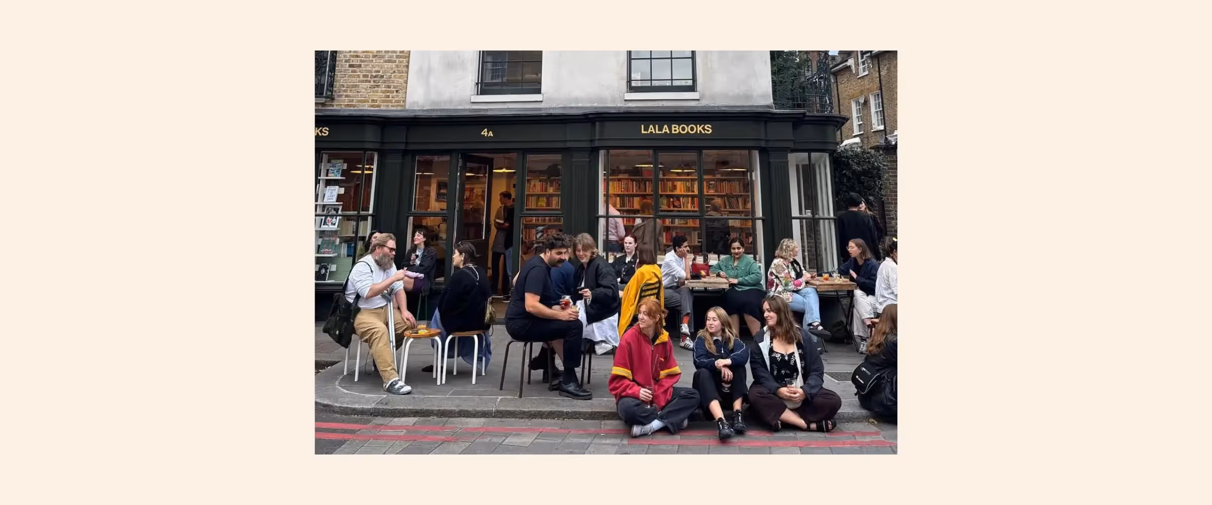 Exterior view of Lala Books, London, with people gathered outside at tables in conversation.