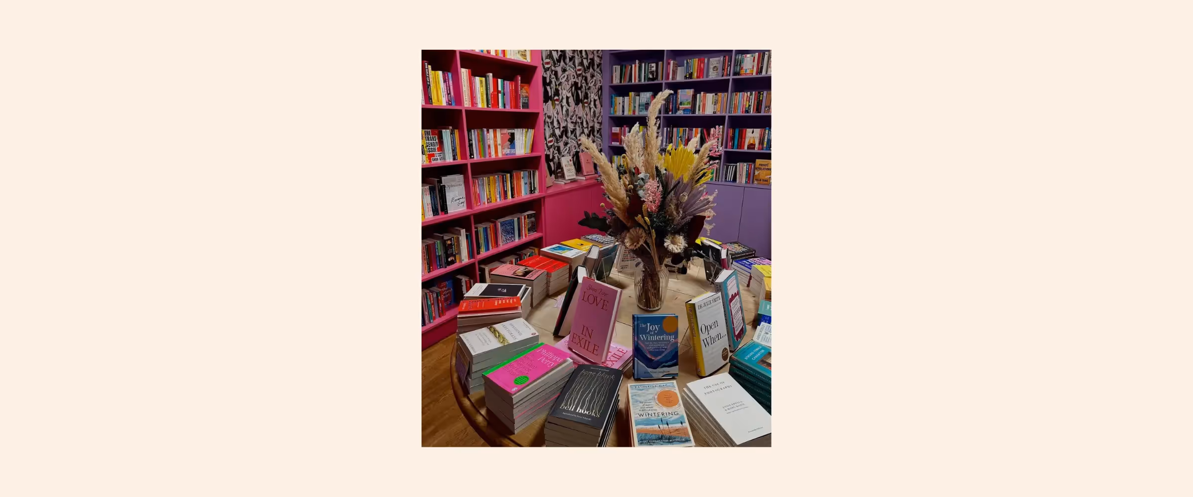 Interior shot of bookshelves and table covered in books at Rare Birds Books, Edinburgh, in shades of vibrant pink and purple.
