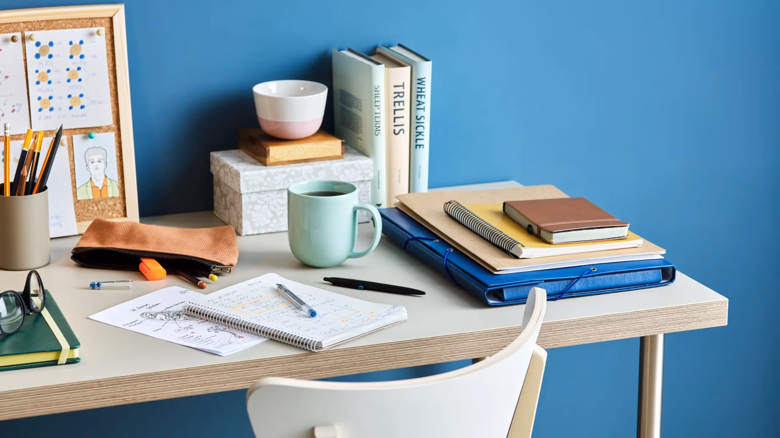 A writer's desk with a notebook for outlining a book against a blue wall background.
