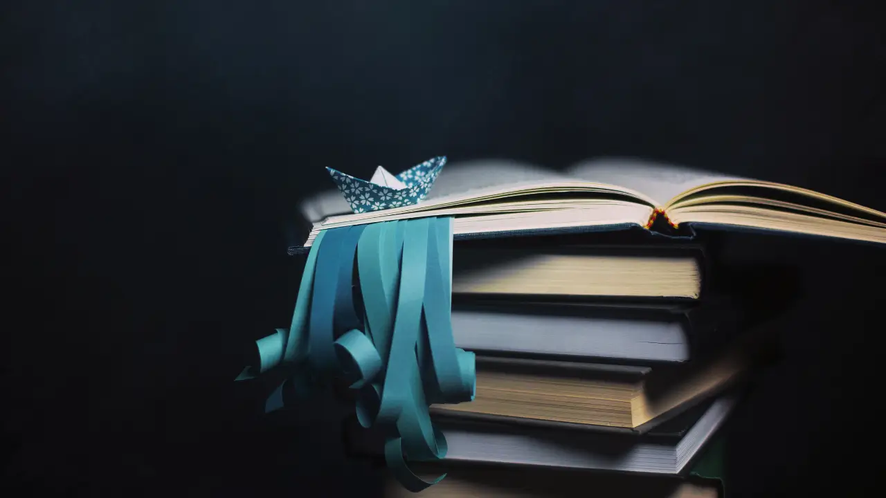 A pile of books with teal-colored ribbons hanging from between the pages.