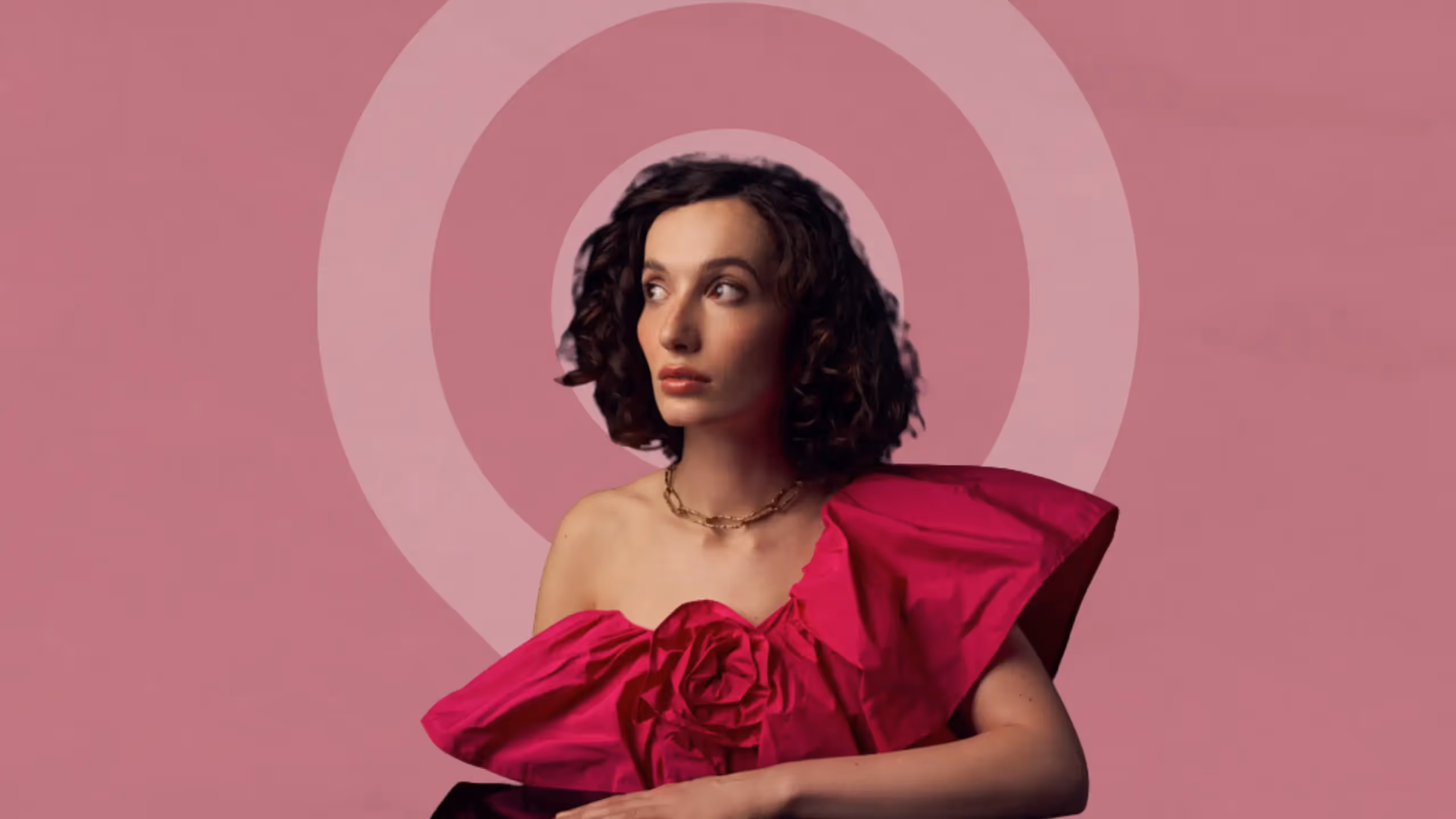 Portrait image of author and writing coach Bea Fitzgerald, wearing a vibrant pink dress, set against a dusky pink background.
