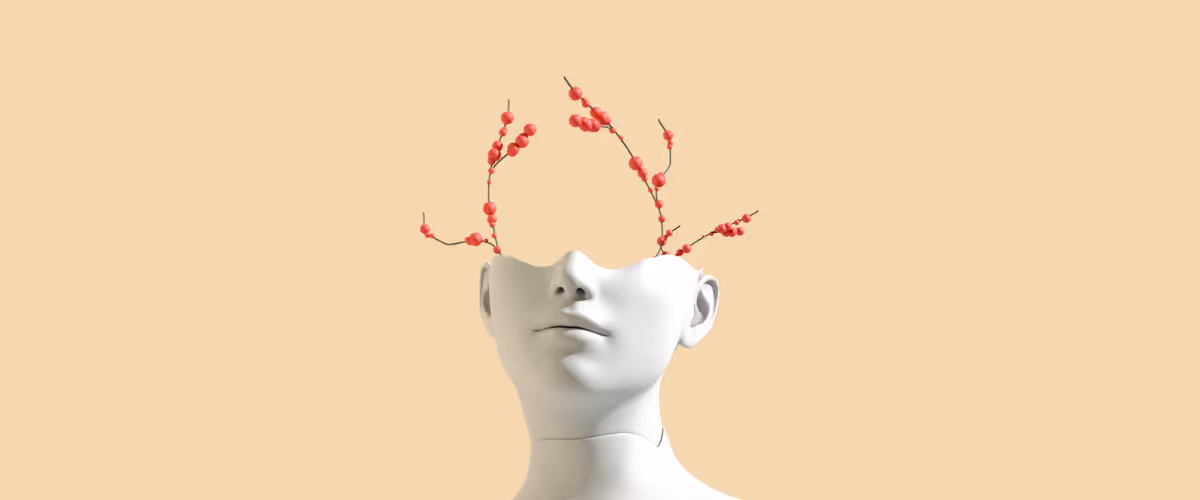 Half of a mannequin head is seen with red berries growing out of it.