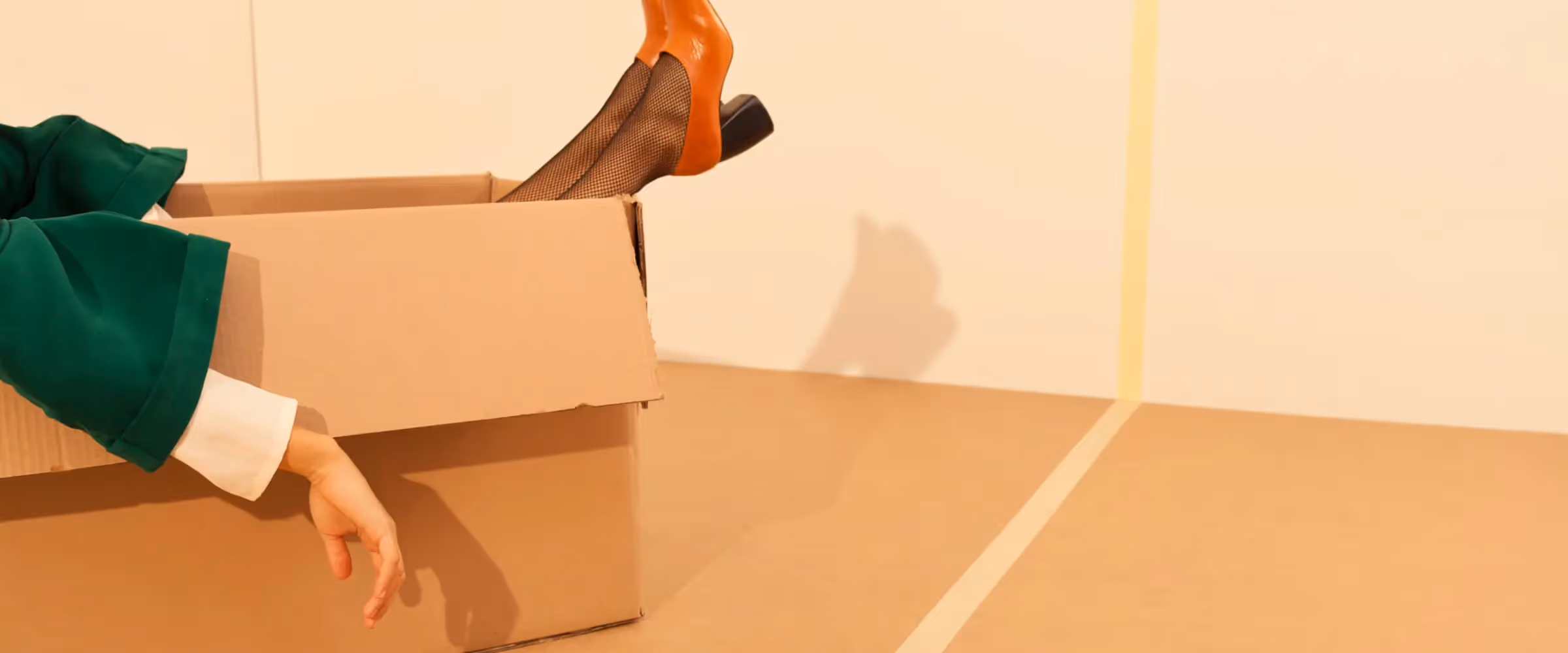 A person sits in a box in a corner.