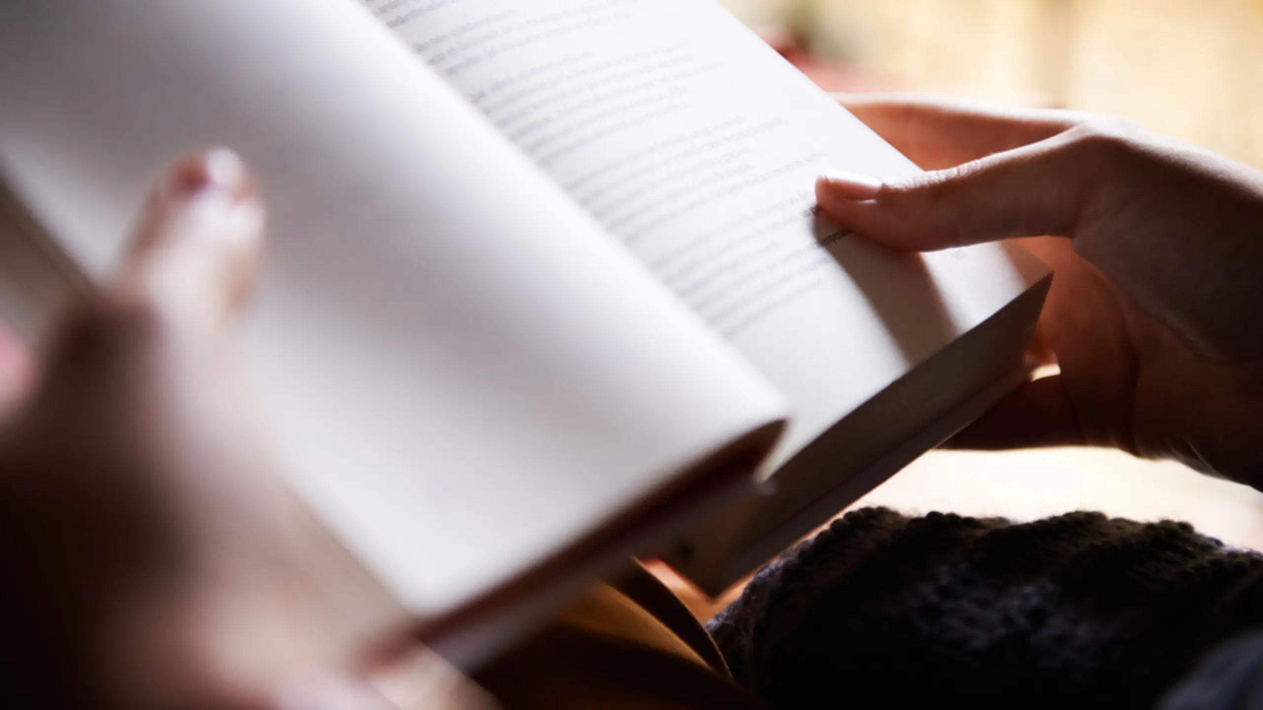 A pair of hands opens a book.