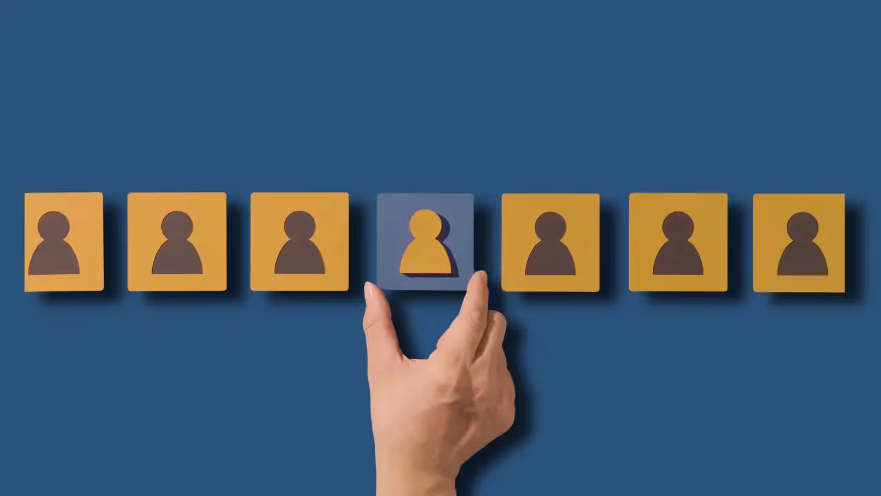 A row of blocks sits on a blue background. The blocks have the silhouettes of figures on them. A hand is picking the middle block.