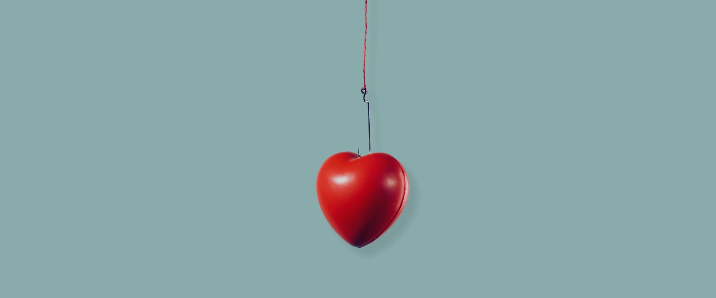 An image of a singular love heart hanging from a hook.