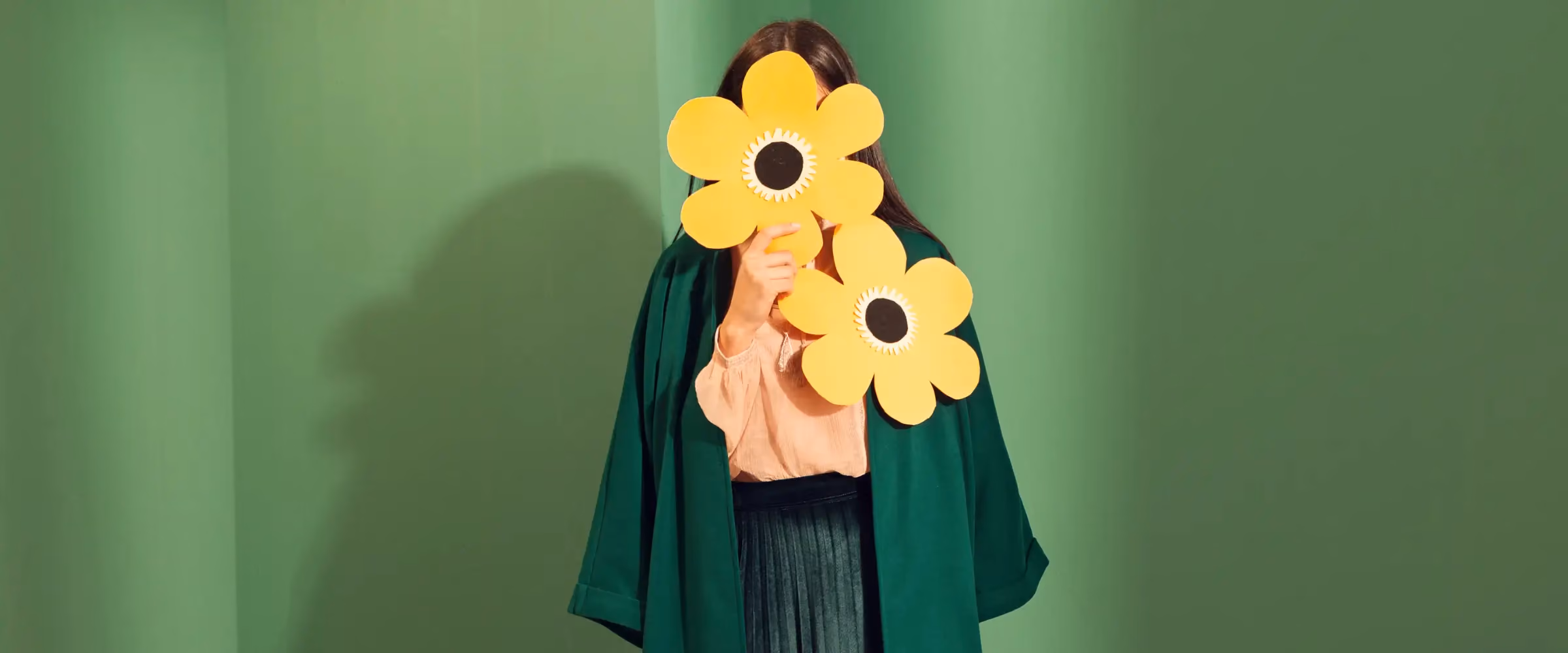 A woman in a green coat is obscured by flowers.