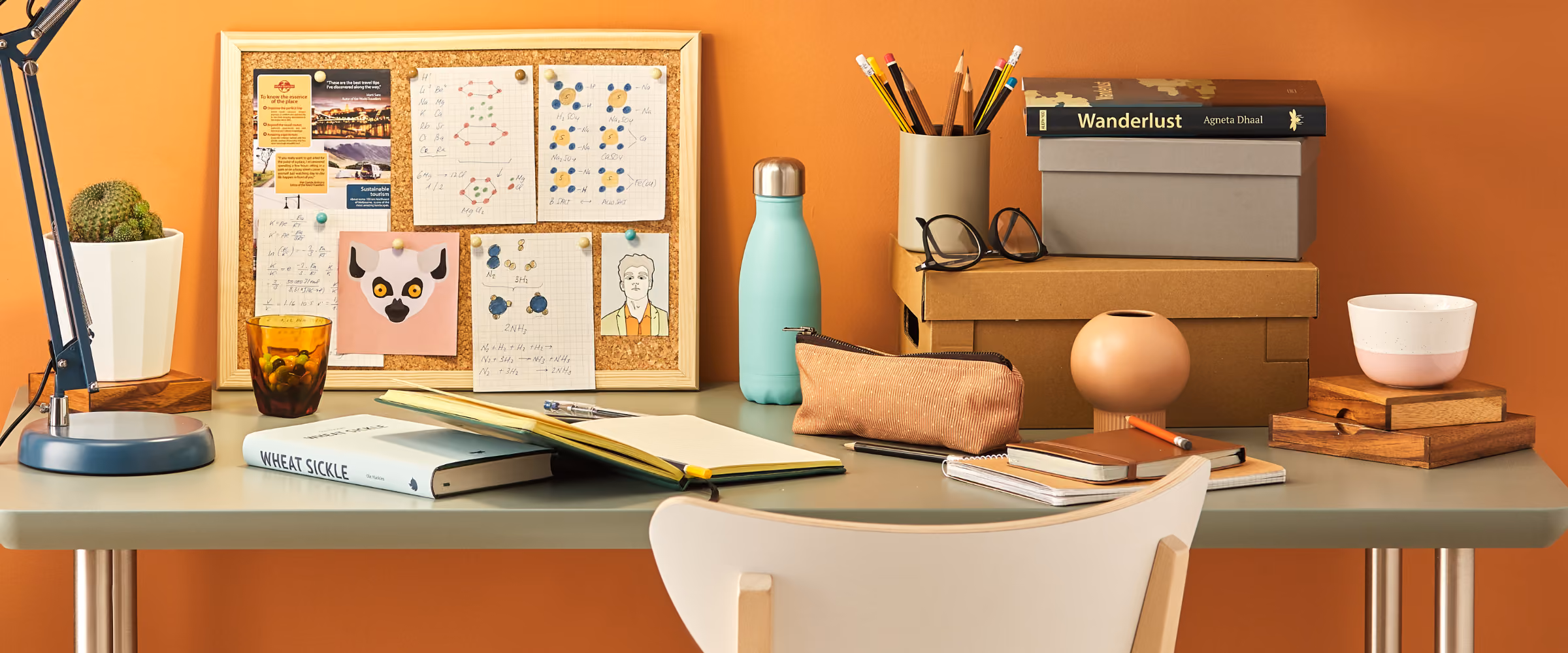 A very full desk is seen, with books, stationery, a corkboard, and much more.