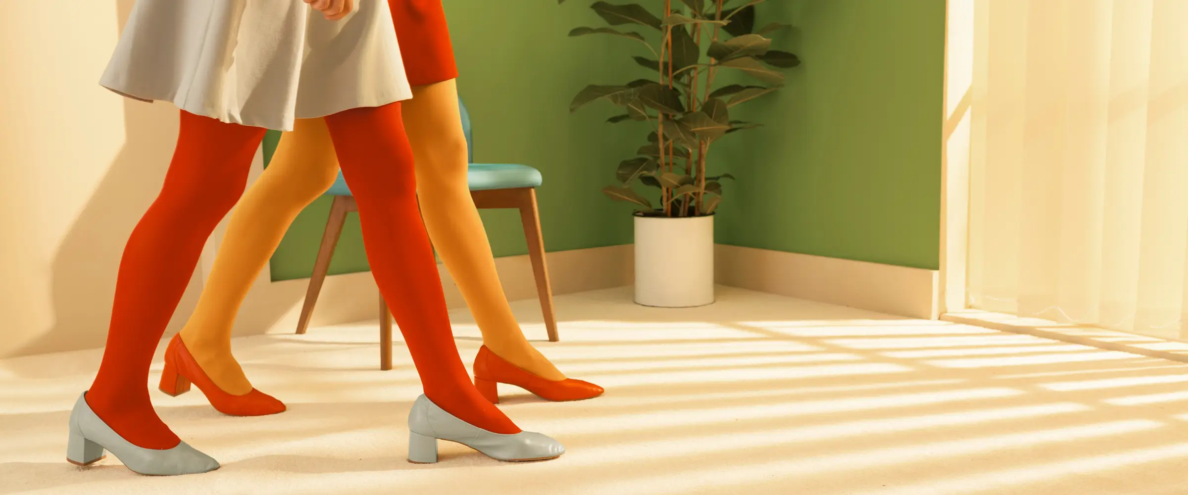 Two women in colorful outfits (shown as just skirts and legs) are walking through an office, with purpose.