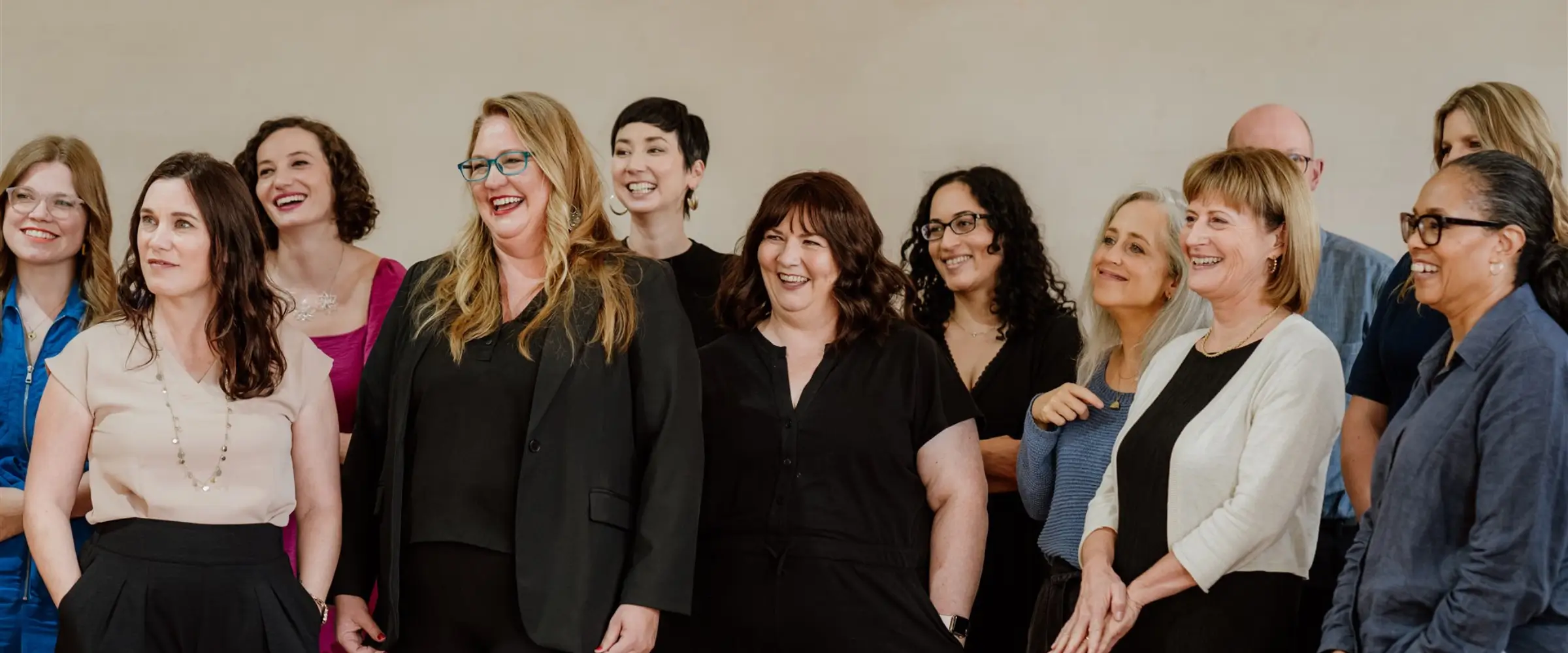 A group of The Novelry coaches stand together, smiling against a wall.