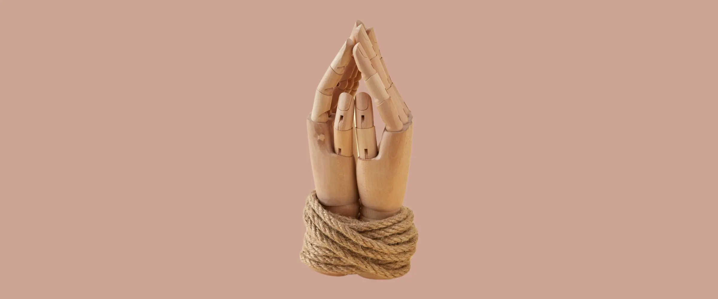 Wooden poseable hands bound together in prayer position by a thin rope.