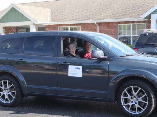 A man helping his passenger get out of the vehicle.
