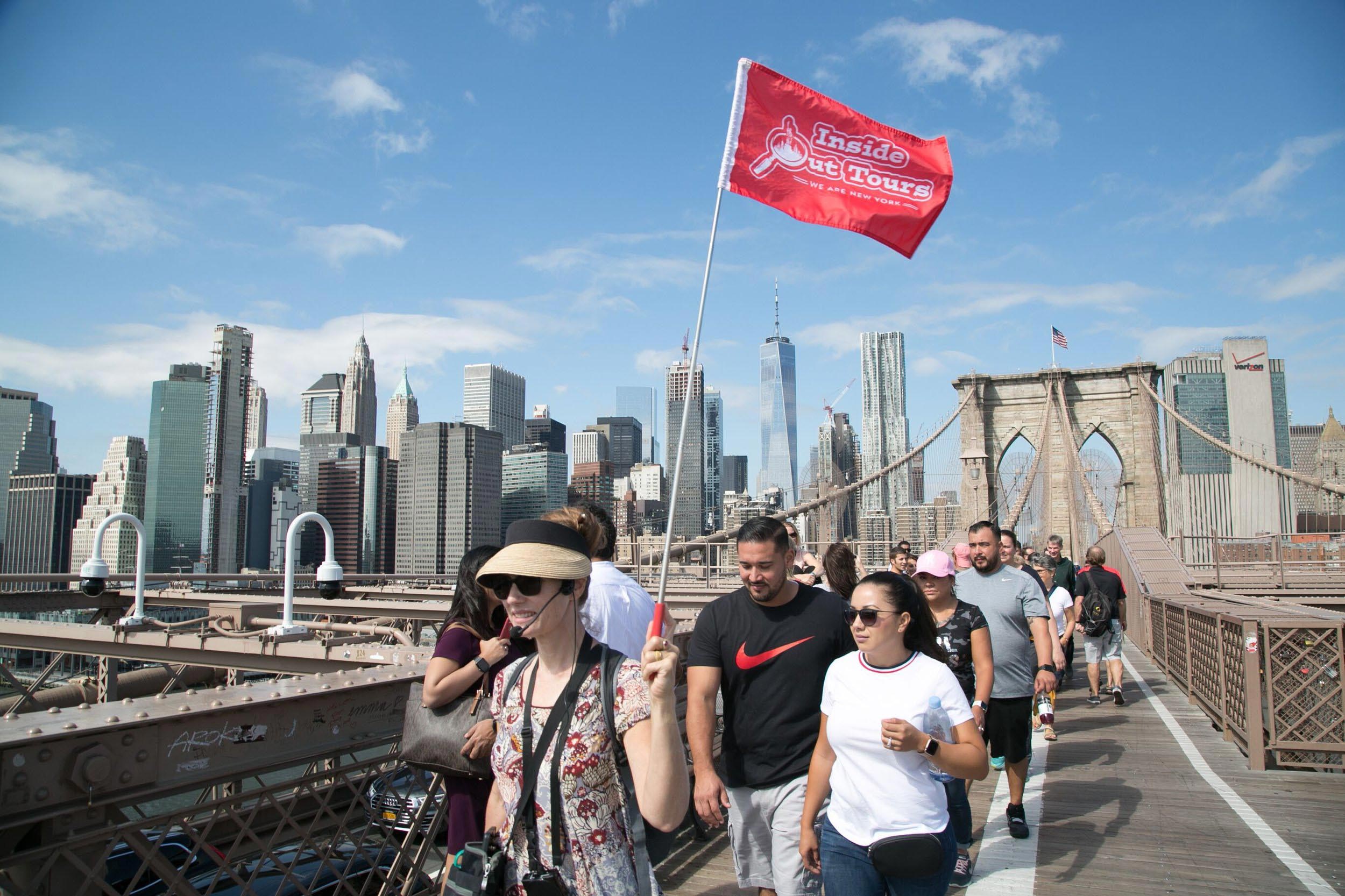 Group of people following their guide with a red flag that reads 'Inside Out Tours"