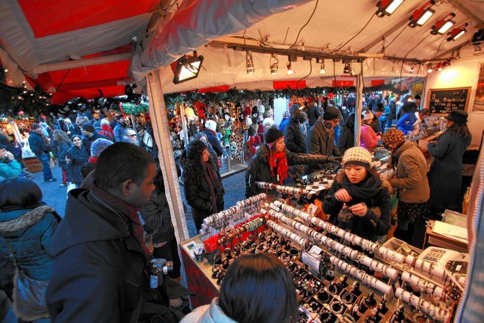 A crowd of people at a holiday market, browsing through hand-crafted goods.
