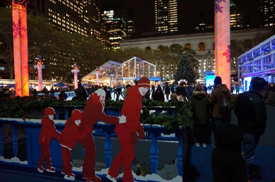 A crowd skates at an ice rink in the middle of New York City.