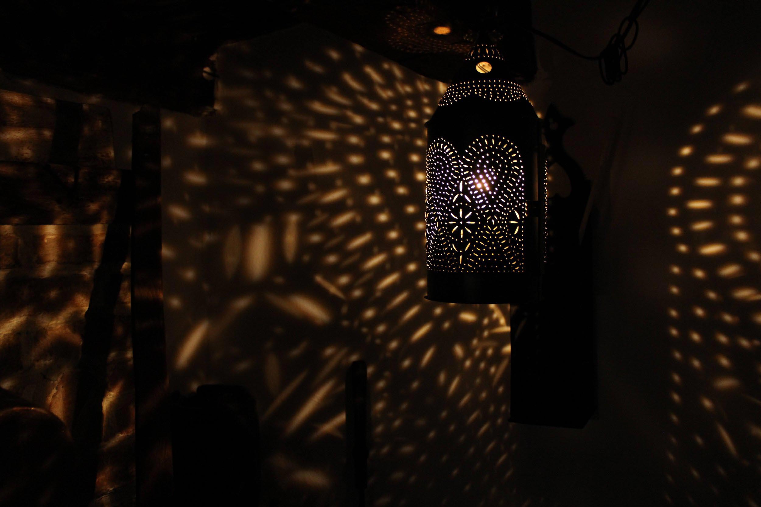 A vintage lantern reflects a pattern of light on the dark surrounding walls.