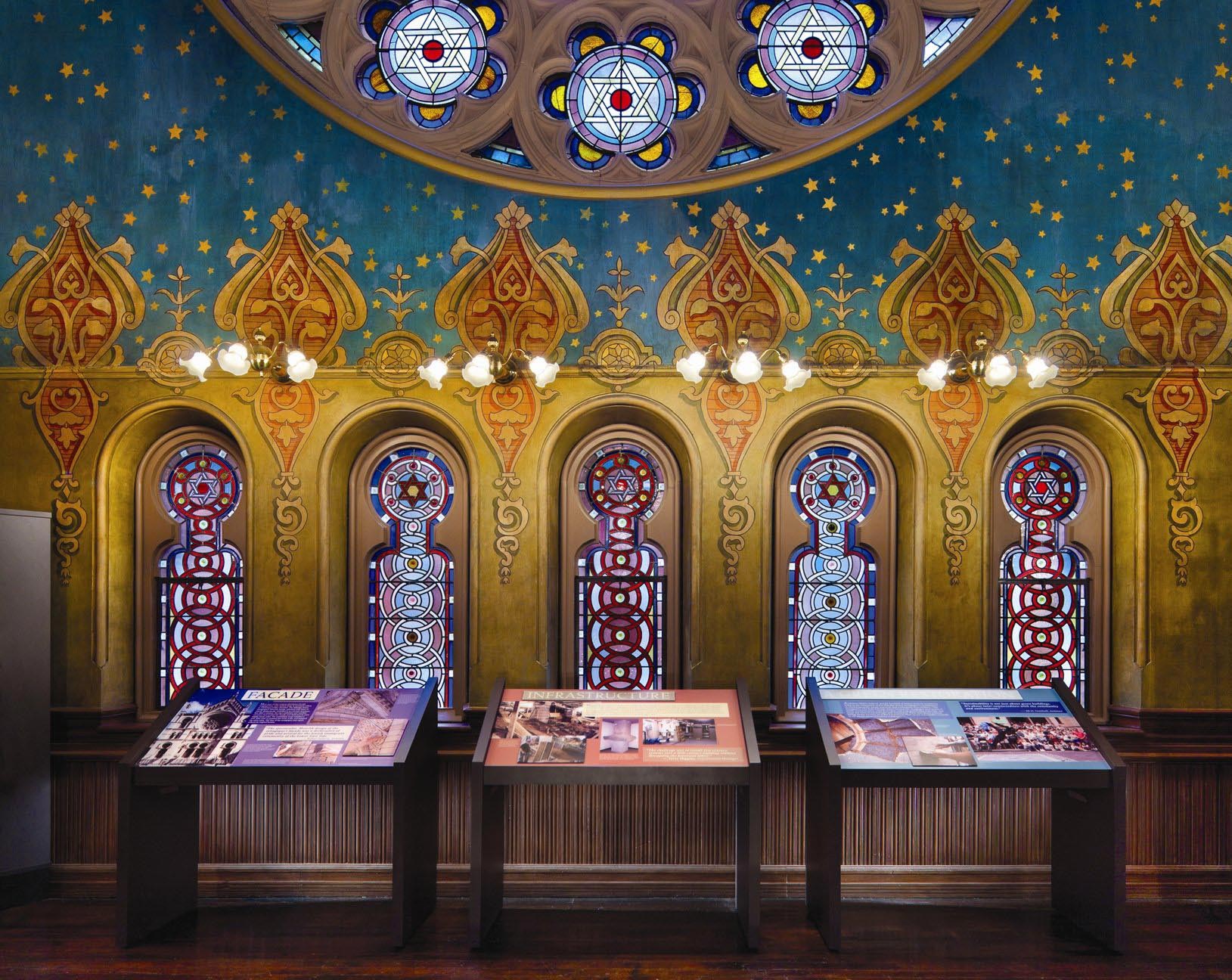 An exhibit provides information about the synagogue in view of intricately painted walls and stained glass.