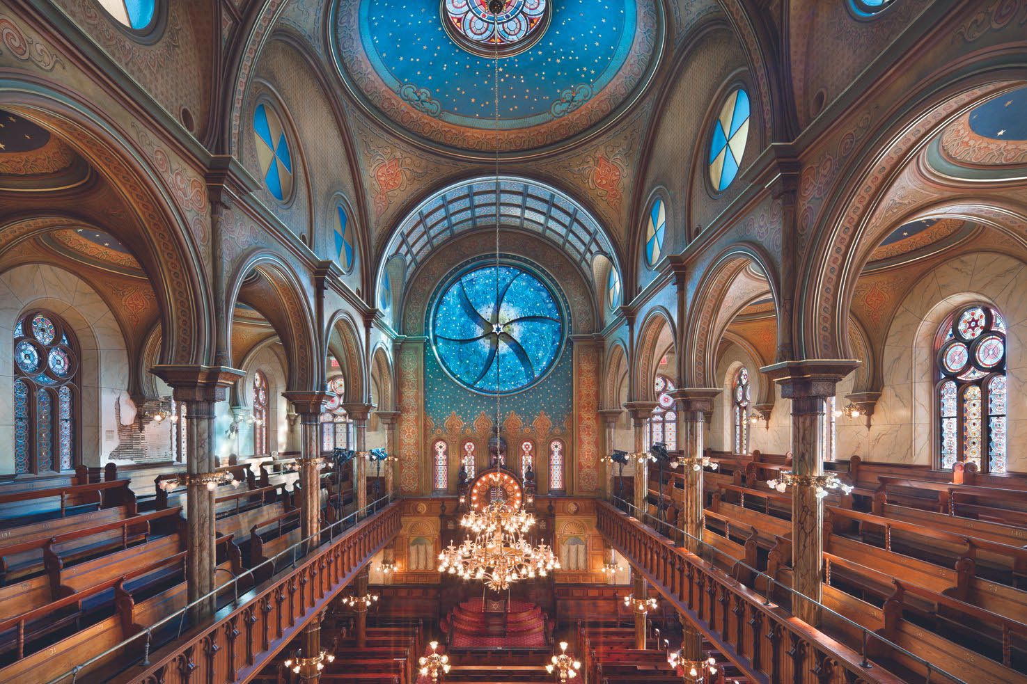 A wide shot of the interior of the museum shows tall ceilings with spherical domes, and a stained glass monument featuring a Jewish star as the centerpiece.