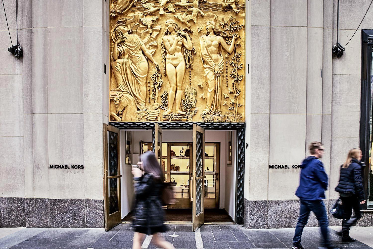 The bottom half of "Friendship Between America and France," a massive gilded panel is visible above the door of a Michael Kors store.