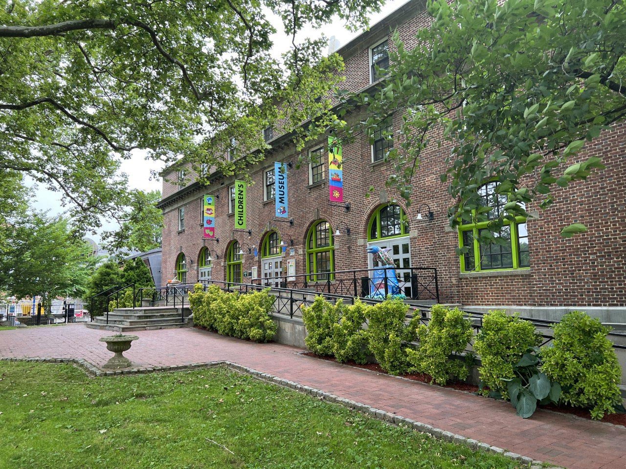 The brick exterior of the museum holds flags that say "Children's Museum" and overlooks a brick courtyard.