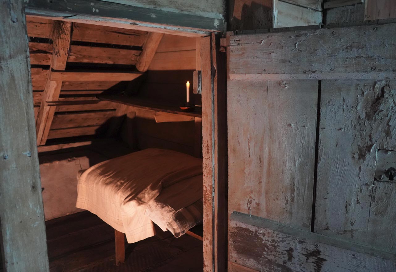 A doorway opens to reveal a dark cupboard with linens and a candle.
