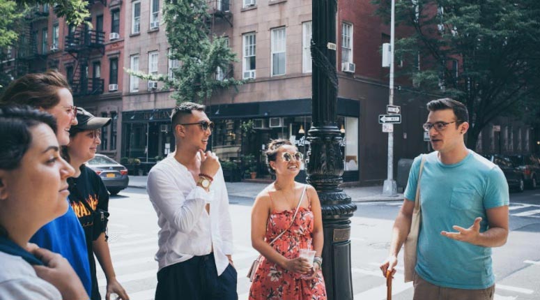 A group of people smile as a tour guide speaks.