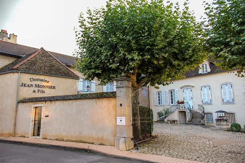 Entrée du Domaine Jean Monnier & Fils à Meursault, façade en pierre et portail donnant sur la cour.