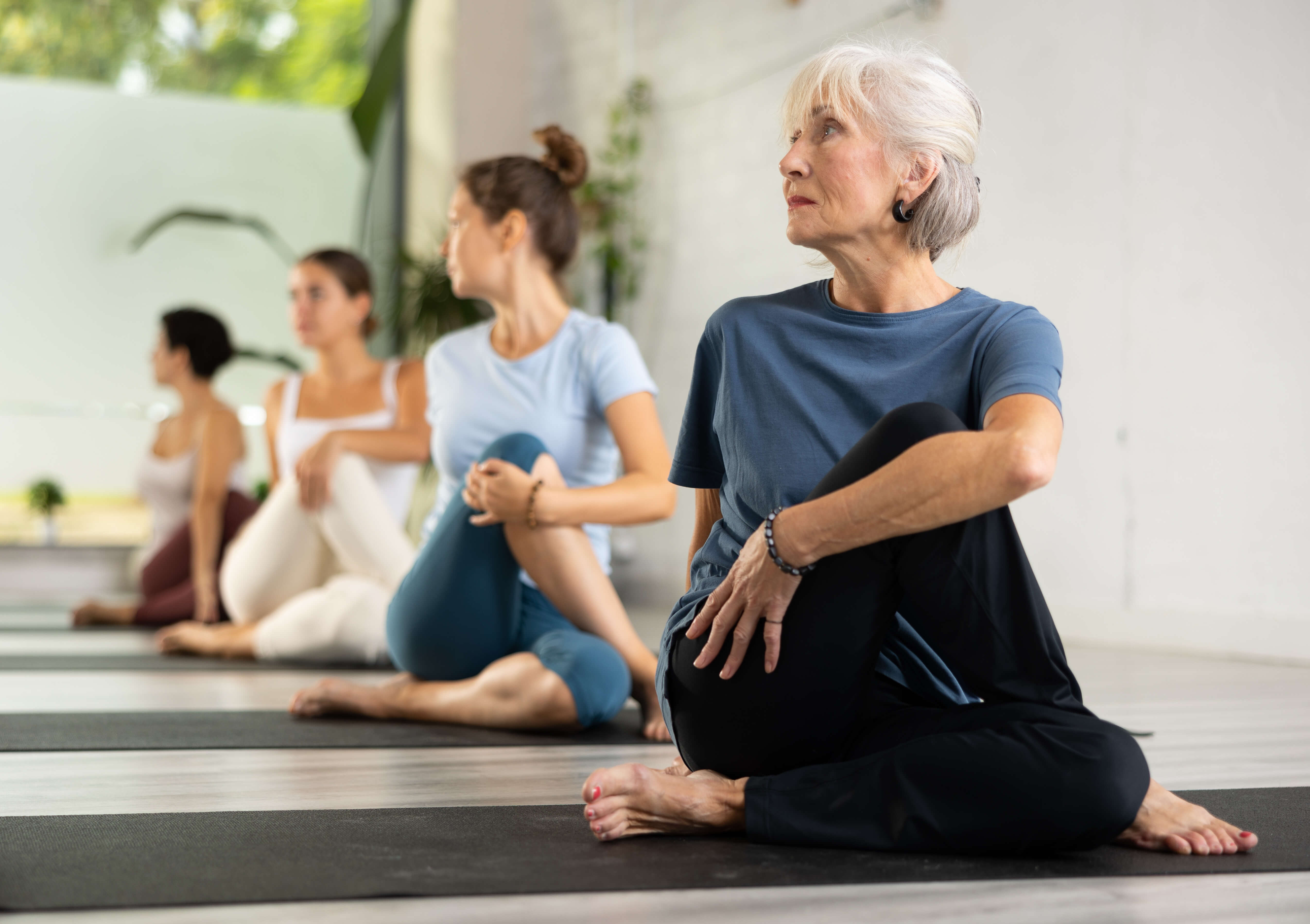 Eldre dame med grått hår i sittende yogaposisjon. 