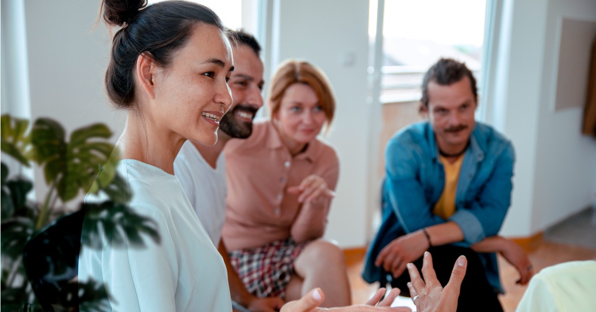 Quatre personne réunies qui parlent et regardent une cinquième personne non visible
