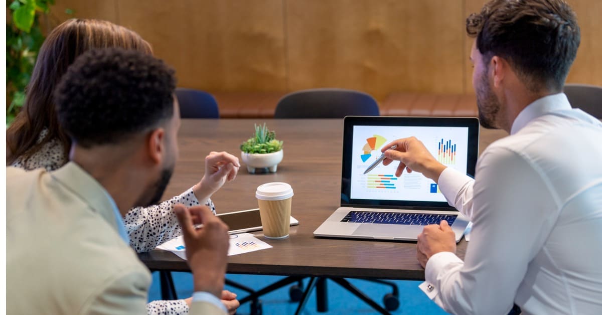 3 personnes de dos regardant un ordinateur avec des graphiques