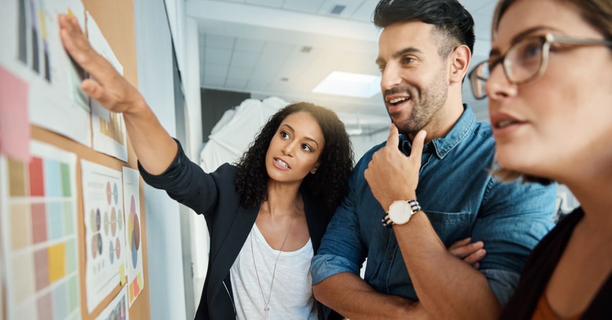 trois personnes parlent devant un tableau d'idées