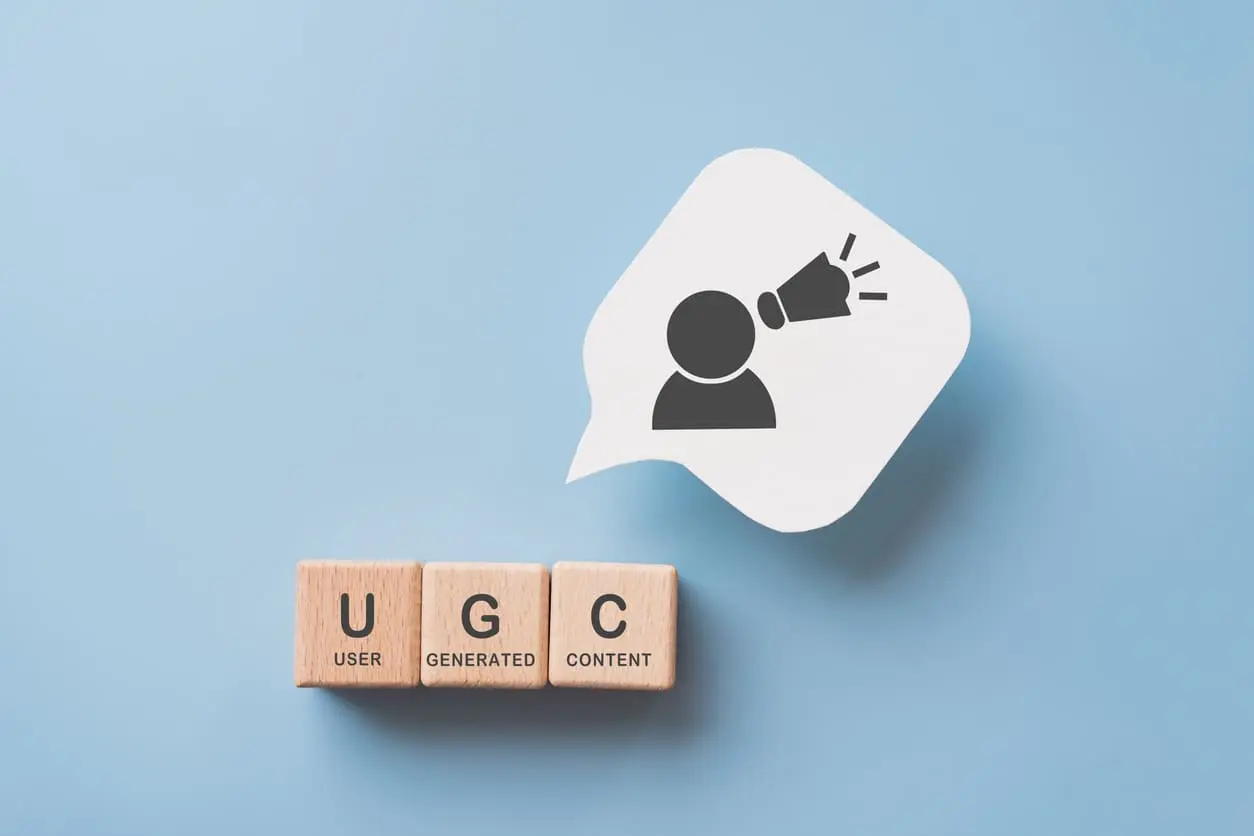 Pour le concept de contenu généré par l’utilisateur. Blocs cubiques en bois avec texte UGC et abréviation, papier bulle blanc avec icône
