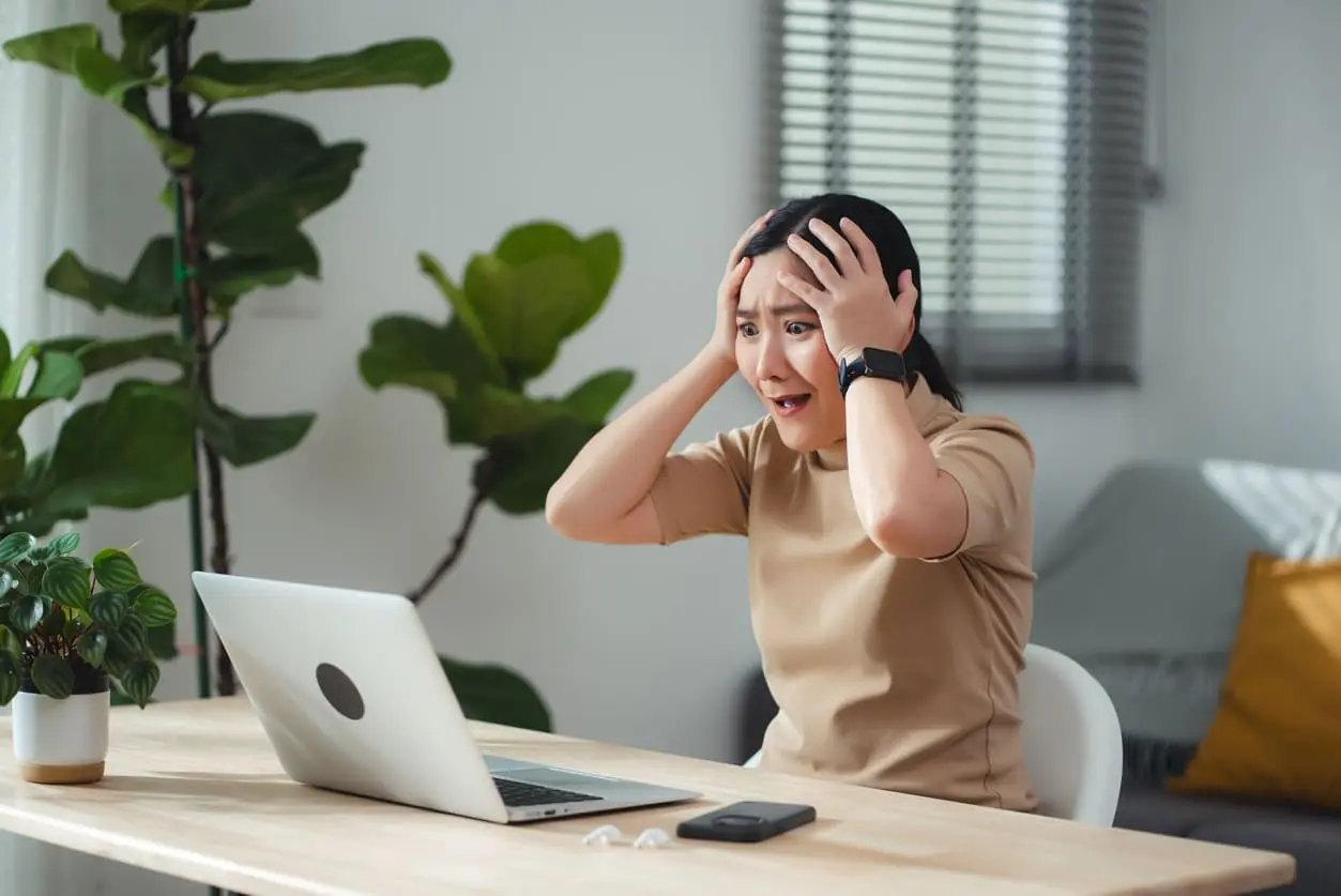 Woman Behind Computer Puting Her Hands on Her Head