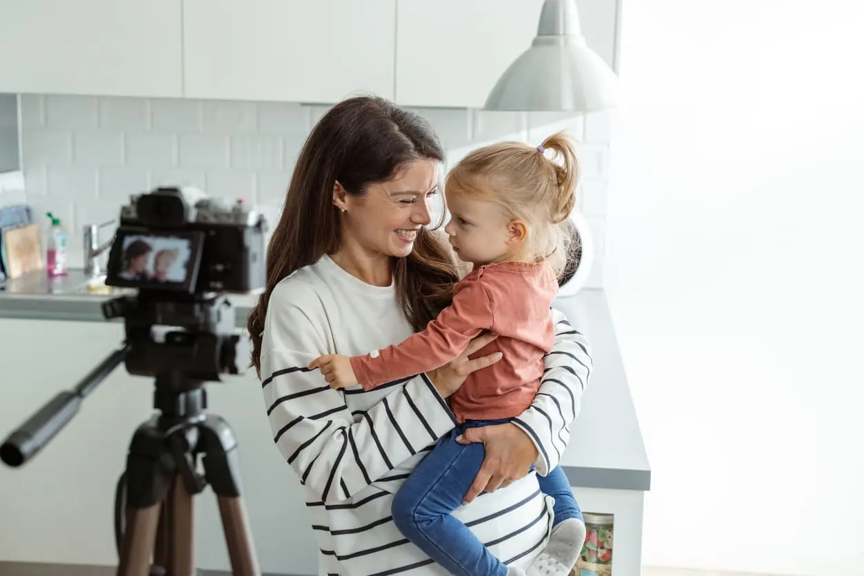 Smiling mother and daughter while recording a video at home