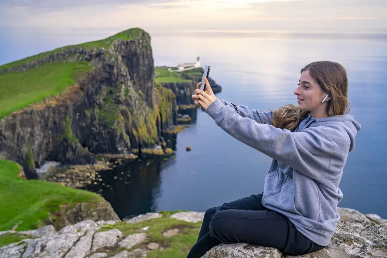Girl taking a selfie photo on smartphone on the Isle of Skye Nest Point Highlands Scotland
