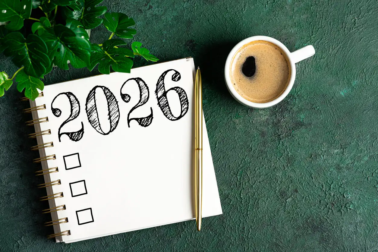 Resoluciones de Año Nuevo 2026 sobre el escritorio. Lista de resoluciones para 2026 con cuaderno y taza de café sobre la mesa. Metas, resoluciones, plan, acción, concepto de lista de verificación. Plantilla para el Año Nuevo 2026