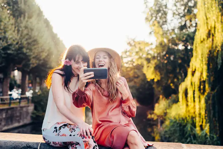 Deux jeunes femmes heureuses prenant un selfie à l’extérieur par une journée ensoleillée