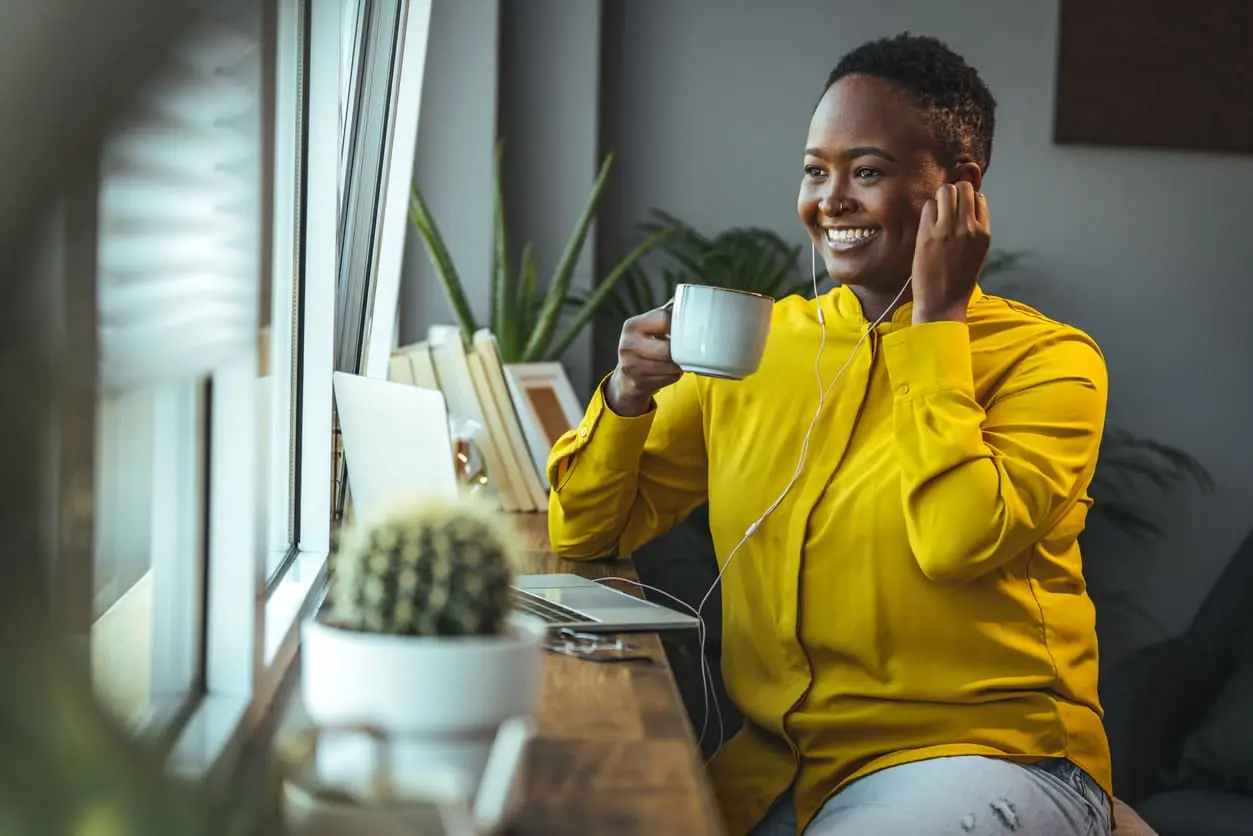Femme buvant une tasse de café à la maison et travaillant sur son ordi