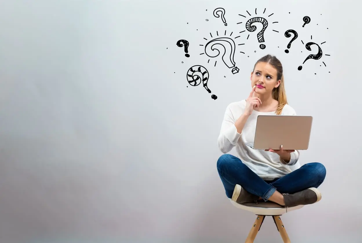 Signos de interrogación con la joven usando su portátil