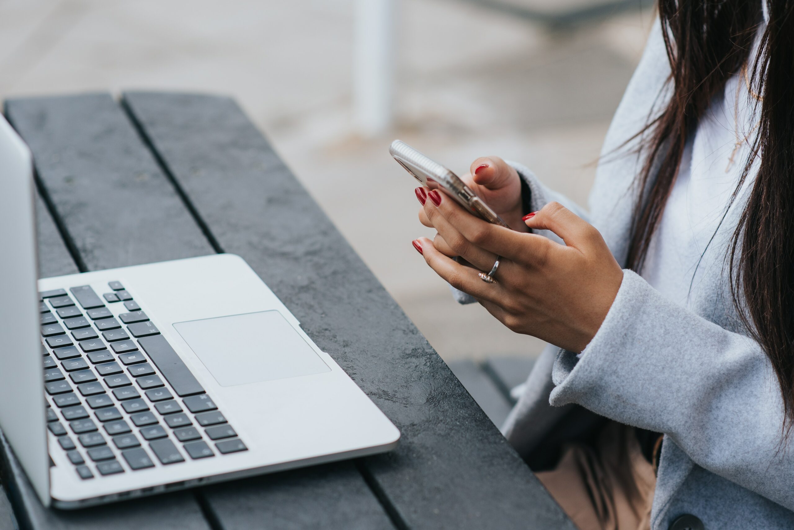 manos de una mujer sosteniendo un teléfono delante de un macbook