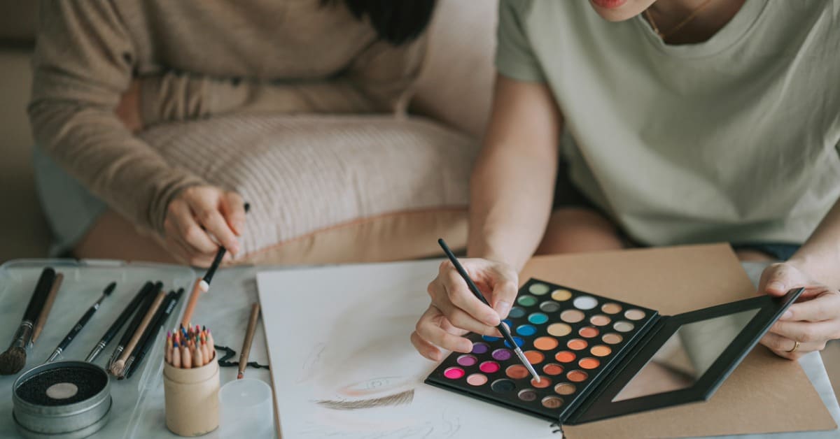 Dos mujeres usando una paleta de sombras de ojos