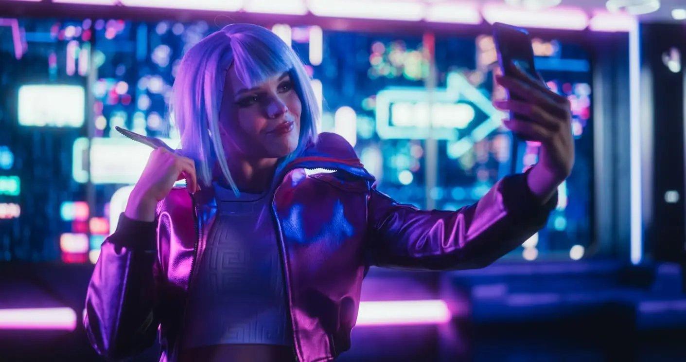 Portrait d’un magnifique créateur de contenu prenant des photos selfie sur smartphone. Jeune femme faisant du cosplay cyberpunk dans des vêtements élégants et des cheveux bleus. Femme Gamer debout dans une salle au néon futuriste