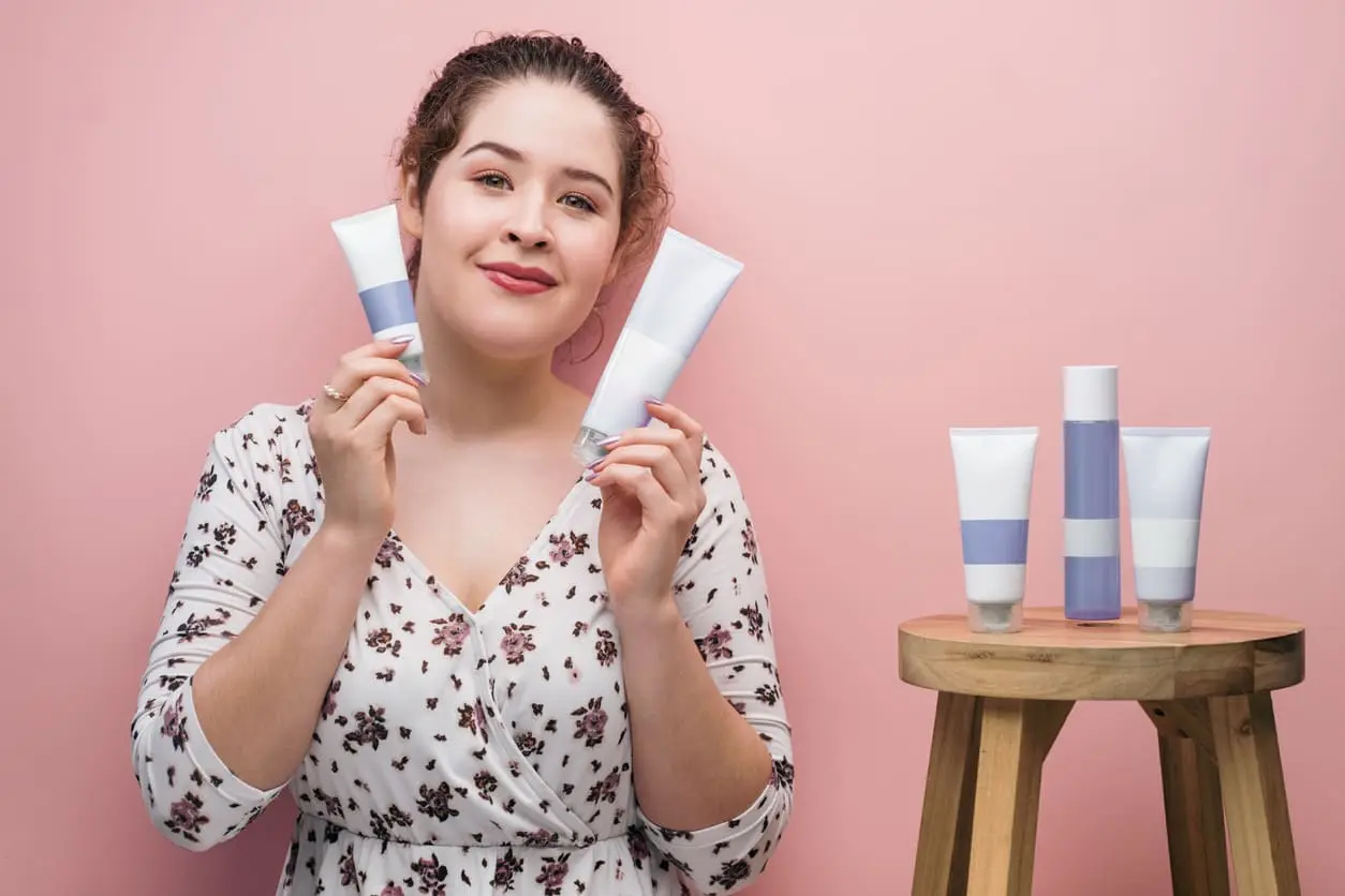 Joven latina que sostiene cosméticos y mira a la cámara