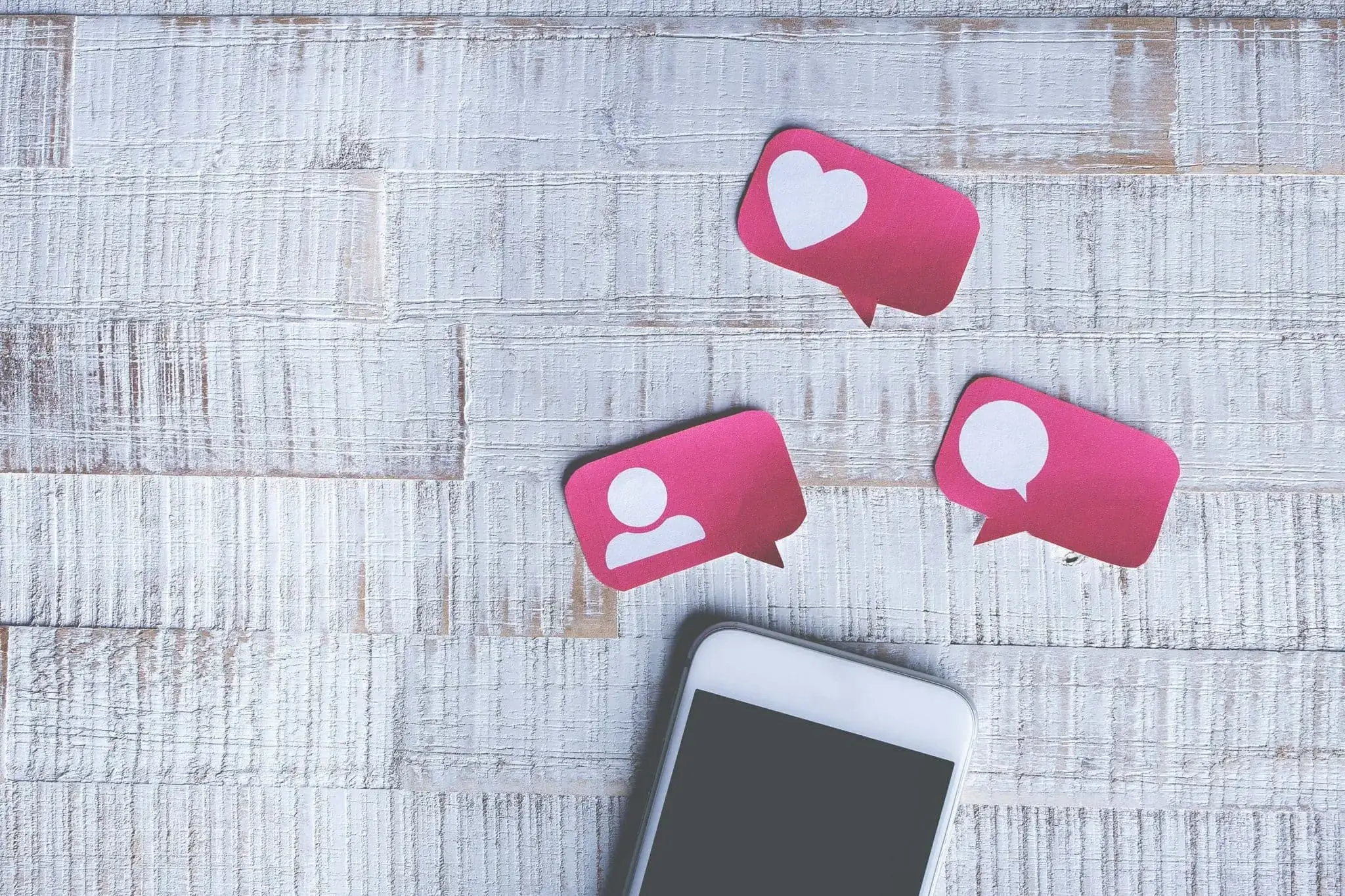Teléfono colocado sobre una mesa con pegatinas de corazón, burbuja y hombre