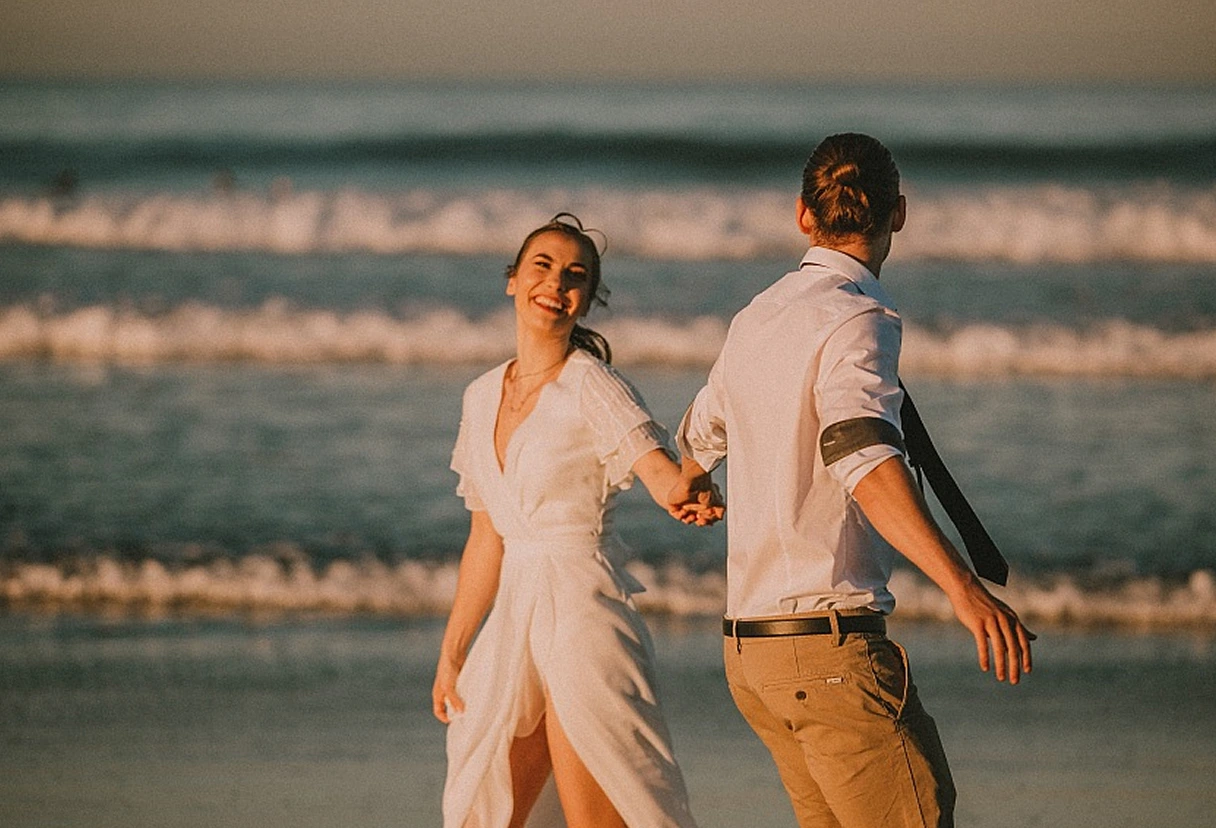A photo of newlyweds running and laughing on the beach