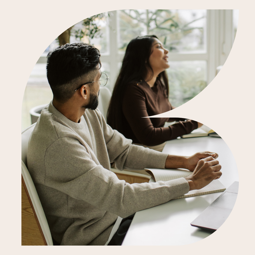 Colleagues participating in a meeting and discussion around a conference table in a modern office.