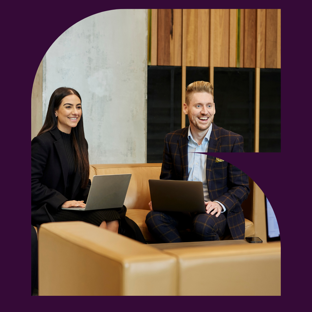 Two seisma employees collaborating with laptops in a modern office lounge.